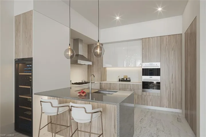 Kitchen with wall chimney range hood, a breakfast bar, white cabinetry, sink, and double oven