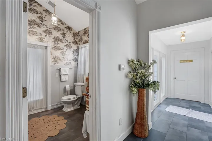 Bathroom with a wainscoted wall, wallpapered walls, and dark tile patterned flooring