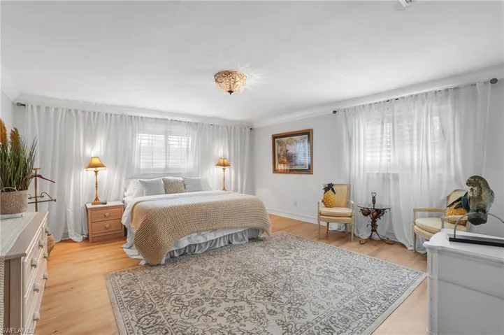 Bedroom with light wood-style flooring and ornamental molding - Virtually Edited Image