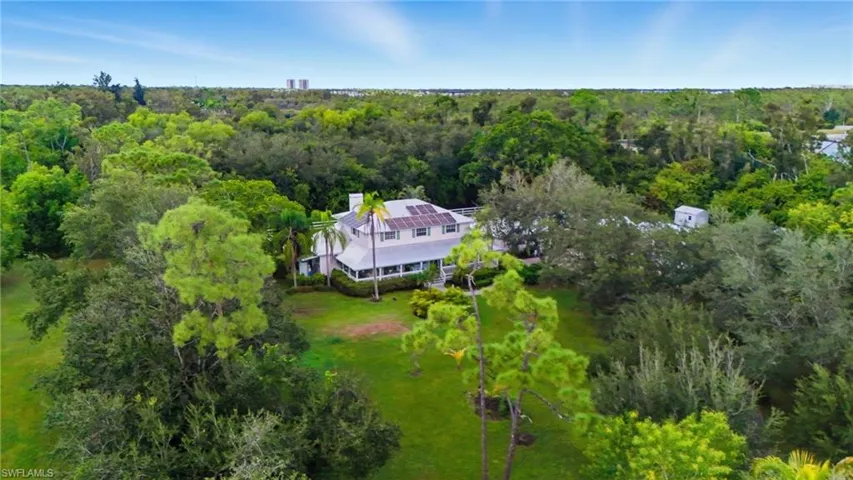 Aerial view of property and surrounding area with a heavily wooded area