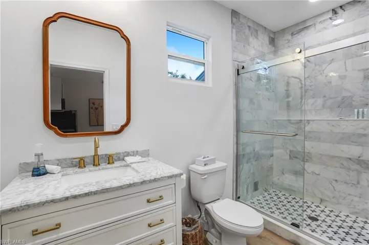 Bathroom featuring vanity and a marble finish shower - Virtually Edited Image