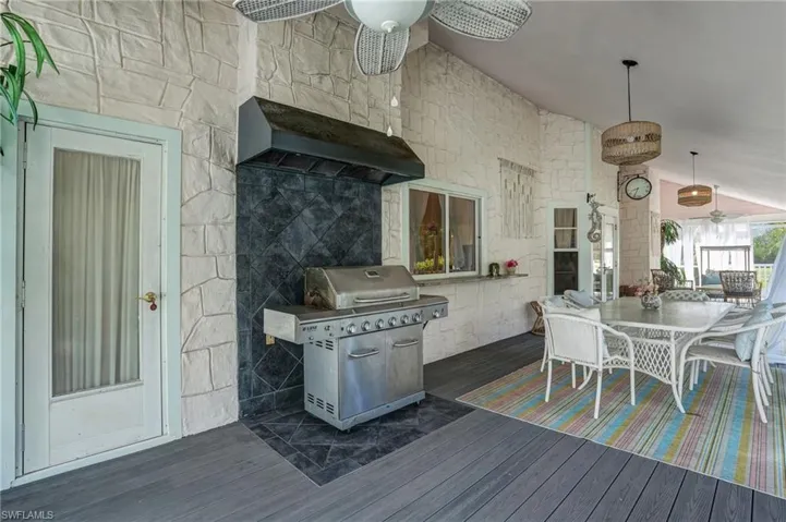 Wooden terrace with outdoor dining area, area for grilling, and ceiling fan - Virtually Edited Image