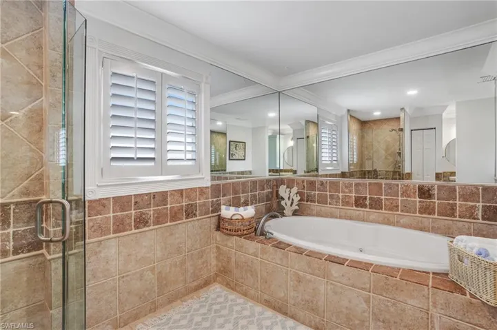 Full bathroom with a stall shower, a bath, crown molding, and tile walls - Virtually Edited Image