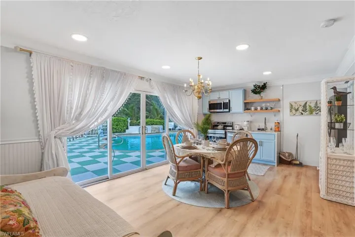 Dining area with light wood-style flooring, ornamental molding, a chandelier, and recessed lighting - Virtually Edited Image