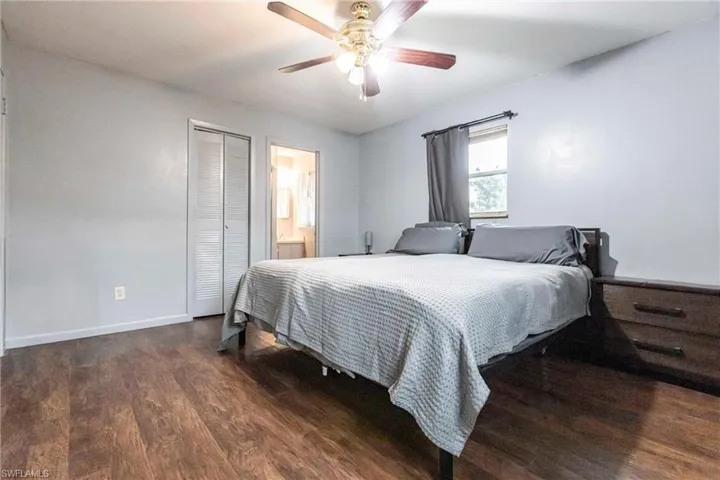 Bedroom featuring ceiling fan, a closet, dark hardwood / wood-style flooring, and ensuite bath