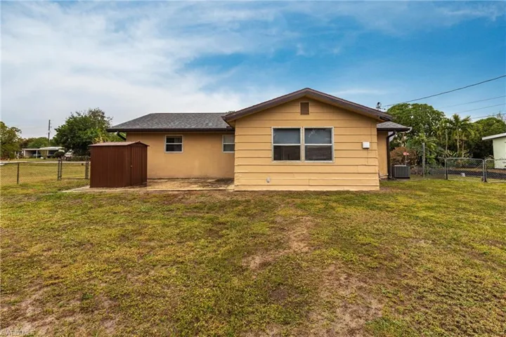 Back of house featuring central AC unit and a yard