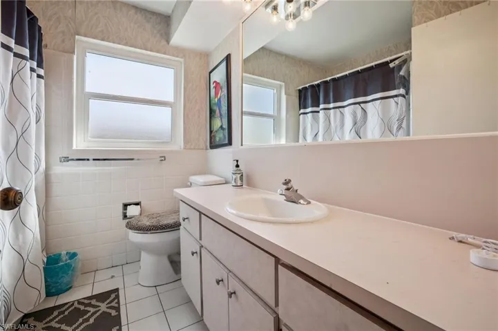 Full bathroom featuring vanity, curtained shower, tile walls, and light tile patterned flooring