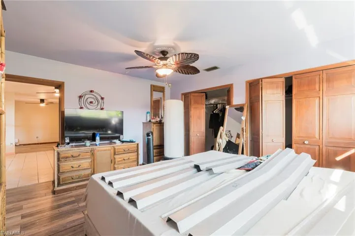 Bedroom featuring two closets, ceiling fan, and wood finished floors