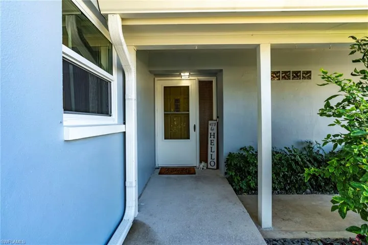 Entrance to property with covered porch and stucco siding