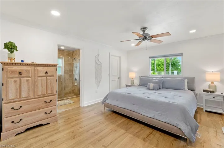 Bedroom featuring ensuite bath, ceiling fan, light wood-type flooring, and ornamental molding