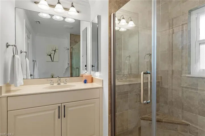 Bathroom with vanity, a shower with shower door, and ornamental molding