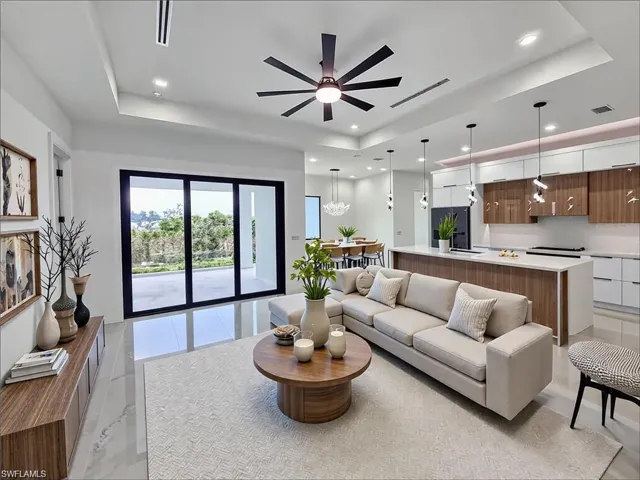 Spacious open-concept living area featuring large sliding glass doors, contemporary ceiling fan, recessed lighting, and a kitchen island with pendant lighting