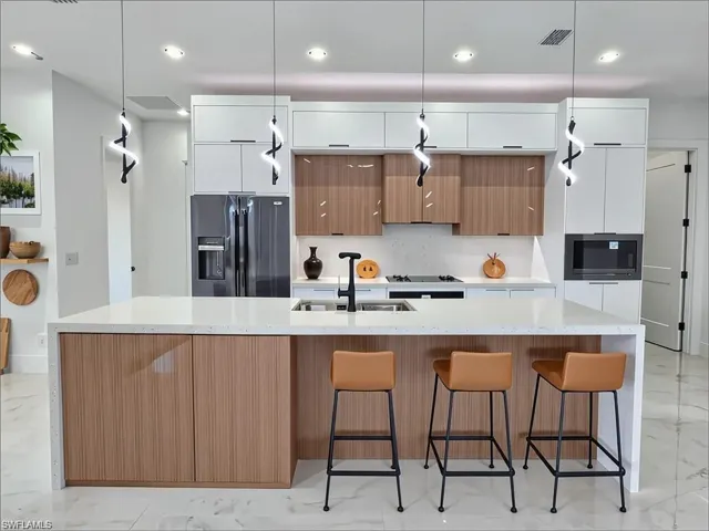 Contemporary kitchen featuring a large island with integrated storage, a double sink with a matte black faucet, and white countertops