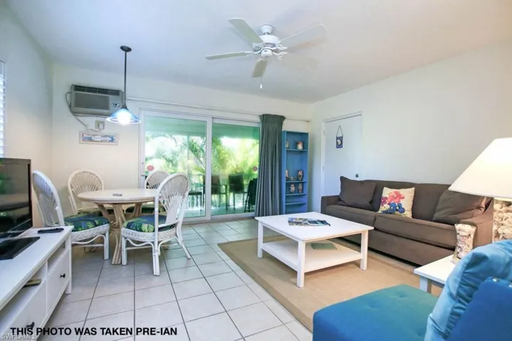 Tiled living room with a wall unit AC and ceiling fan