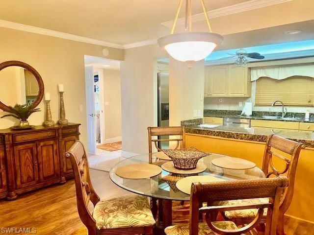 Dining space featuring a ceiling fan, baseboards, ornamental molding, and light wood-style floors