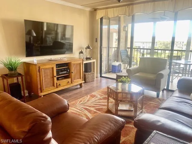 Living area with ornamental molding, wood finished floors, and plenty of natural light
