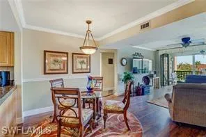 Dining room with dark wood-type flooring, ceiling fan, and ornamental molding