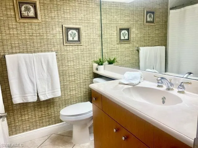 Full bath featuring tile patterned floors, vanity, toilet, and curtained shower