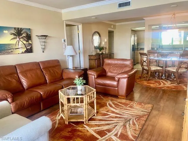 Living room featuring crown molding, a wealth of natural light, wood finished floors, and visible vents