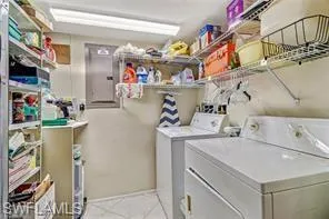 Laundry room with electric panel, washer and dryer, and light tile patterned floors