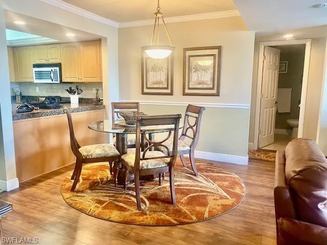 Dining area with crown molding, baseboards, and light wood finished floors