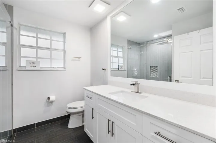 Bathroom featuring vanity, an enclosed shower, and toilet