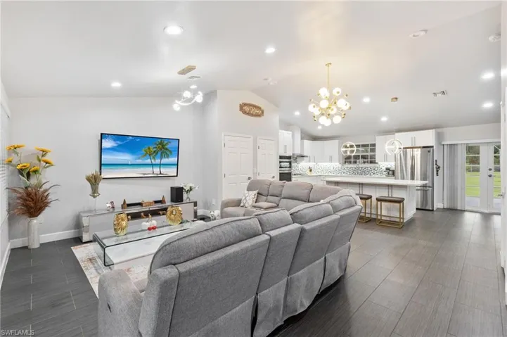 Living room featuring vaulted ceiling, french doors, and a chandelier