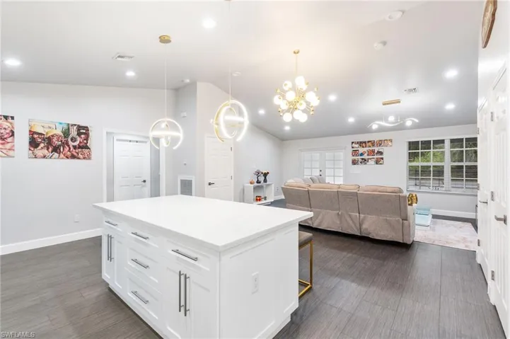 Kitchen with a kitchen island, a breakfast bar, decorative light fixtures, white cabinetry, and lofted ceiling