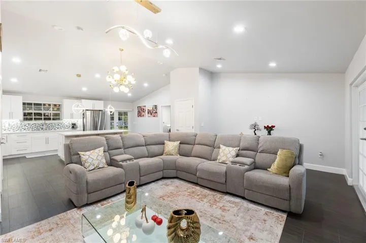 Living room featuring lofted ceiling, dark hardwood / wood-style flooring, and a chandelier