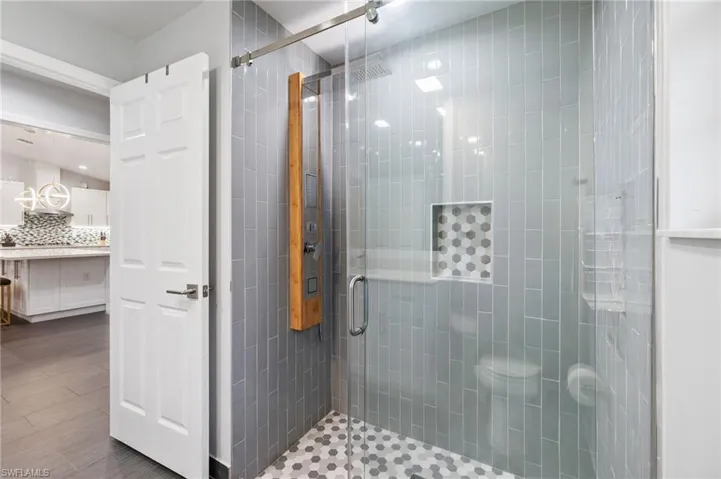 Bathroom with wood-type flooring, an enclosed shower, and decorative backsplash