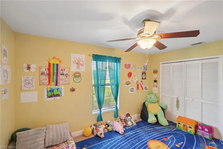 Carpeted bedroom with ceiling fan and a closet