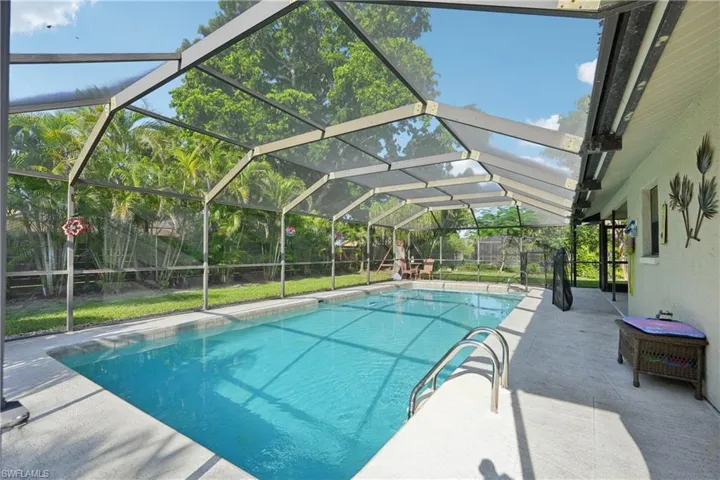 Outdoor pool featuring a patio, a fenced backyard, and glass enclosure