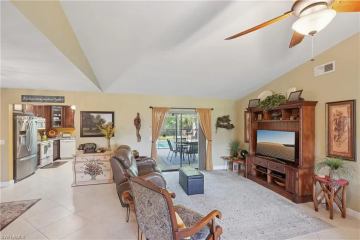 Living area featuring lofted ceiling, light tile patterned floors, and a ceiling fan