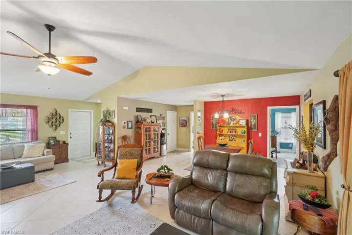 Living room featuring vaulted ceiling, ceiling fan, a chandelier, and light tile patterned floors