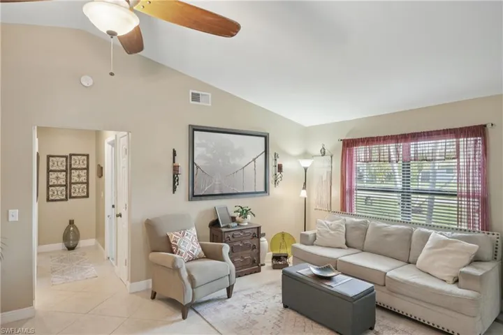 Living area with lofted ceiling, a ceiling fan, and light tile patterned floors