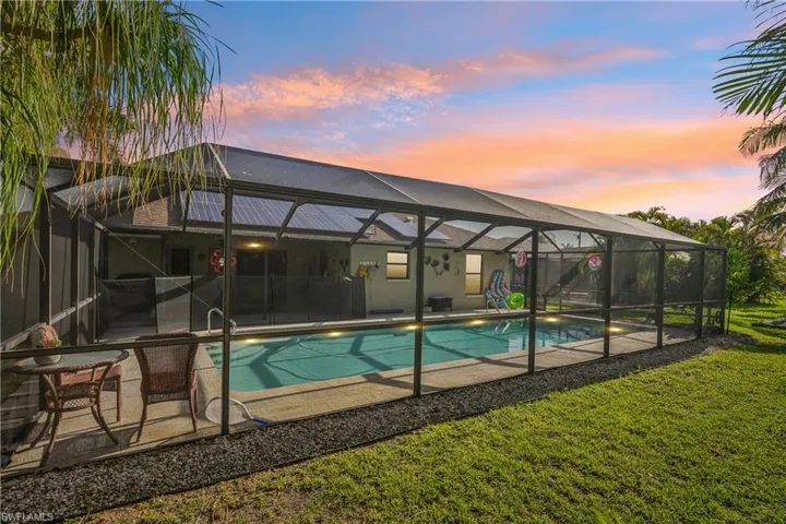 Outdoor pool featuring glass enclosure, a patio, and a lawn