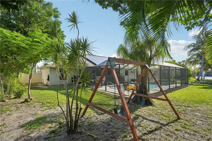 View of play area featuring an outdoor pool, a lawn, and a lanai