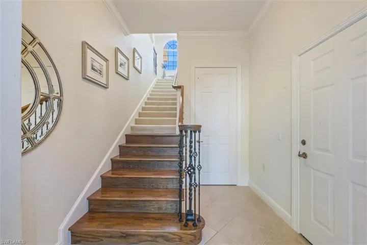 Staircase featuring tile patterned flooring and crown molding