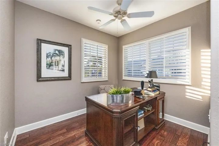 Home office with dark wood-type flooring and ceiling fan