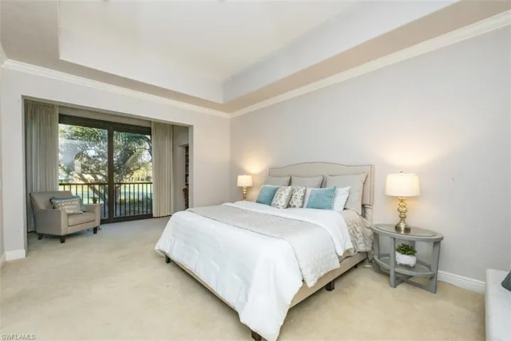 Carpeted bedroom with access to exterior, a tray ceiling, and crown molding