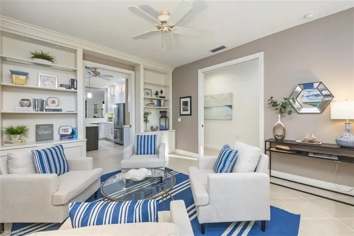 Living area featuring built in shelves, light tile patterned floors, and ceiling fan