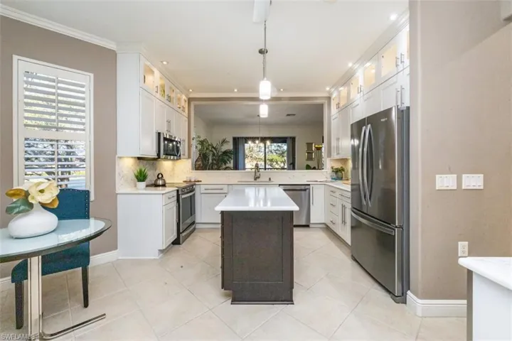 Kitchen featuring stainless steel appliances, pendant lighting, glass insert cabinets, white cabinetry, and a center island