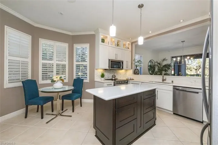 Kitchen with stainless steel appliances, decorative light fixtures, white cabinetry, a kitchen island, and decorative backsplash
