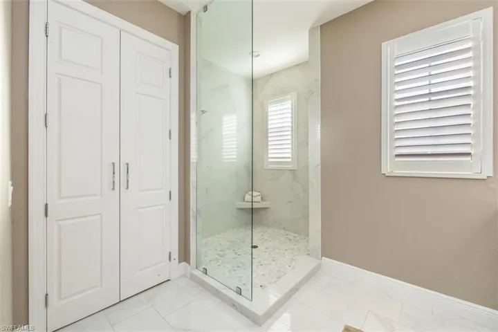 Bathroom featuring marble look tile flooring and a marble finish shower