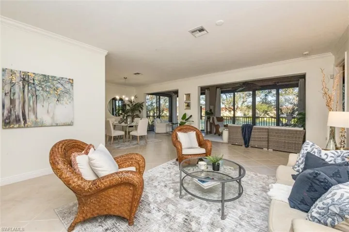 Living area featuring a chandelier, crown molding, and light tile patterned floors