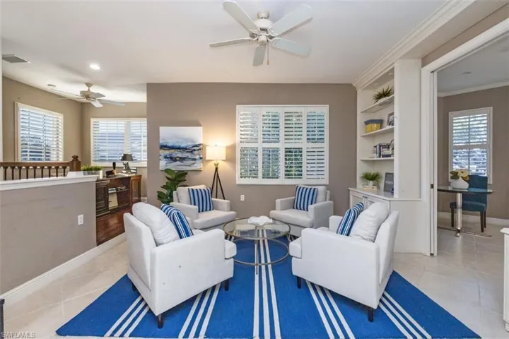 Living room featuring built in features, light tile patterned flooring, and a ceiling fan