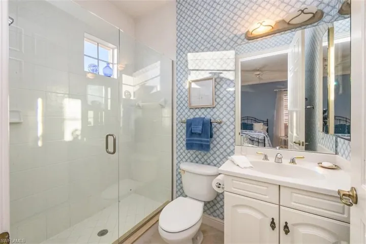Bathroom featuring wallpapered walls, ensuite bath, vanity, and a shower stall