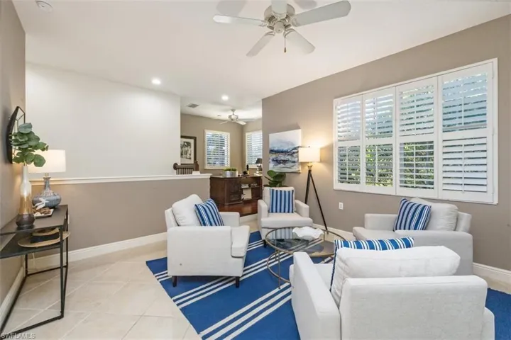 Living room with ceiling fan, light tile patterned flooring, and recessed lighting