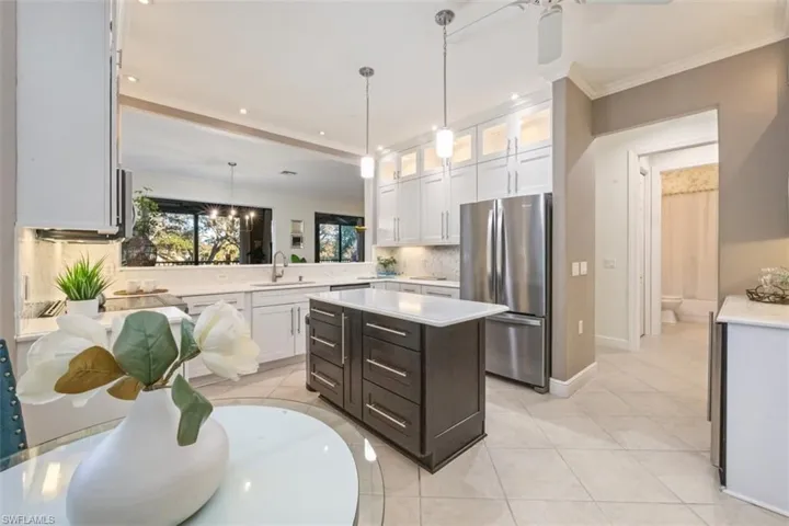 Kitchen with glass insert cabinets, freestanding refrigerator, pendant lighting, white cabinets, and light tile patterned floors