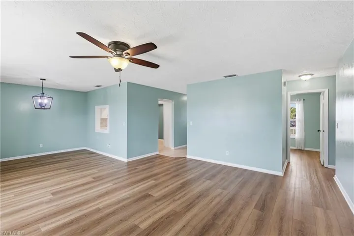 Living room area with fan is open to dining area. Kitchen with pass-through is in left rear. Guest bedroom door is open on the right. NO CARPET! Newer luxury vinyl and tile flooring throughout.